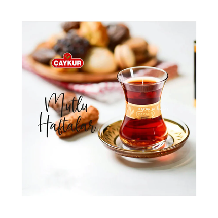 Türkisches Teeglas mit bernsteinfarbenem Tee auf Untertasse, CAYKUR Logo