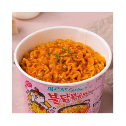 Open pink Buldak Carbonara cup with orange noodles and herbs garnish