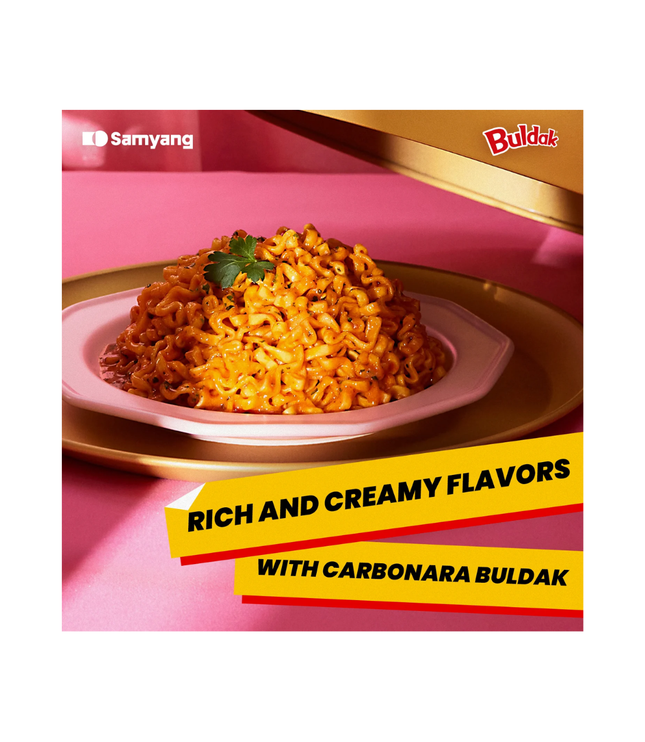 Bowl of creamy orange Buldak Carbonara noodles on a pink label card